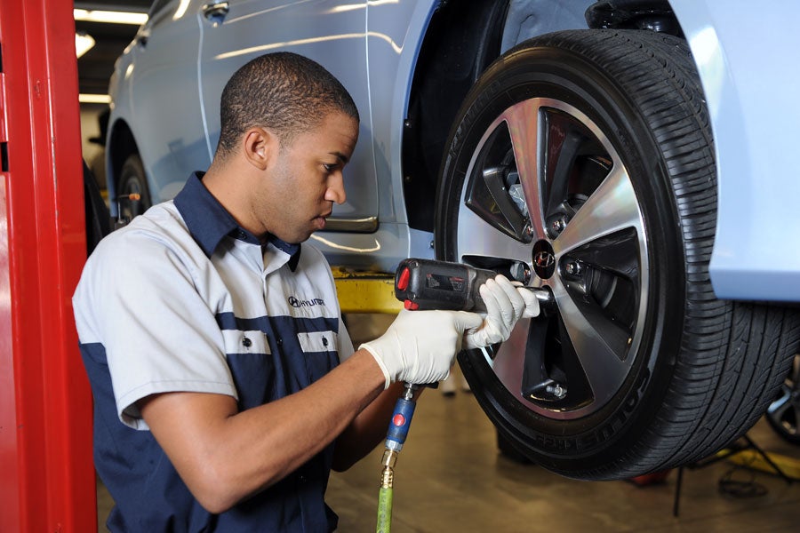 Hyundai-certified technician removing a wheel with an impact wrench during a service appointment